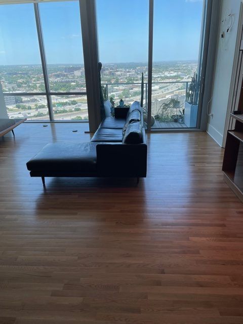 light hardwood flooring with black couch and floor to ceiling windows